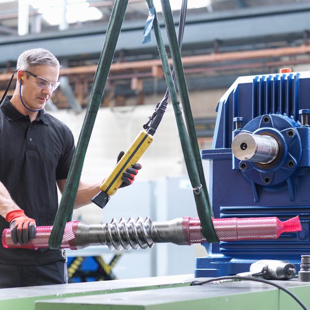 Engineer assembling industrial gearbox in engineering factory