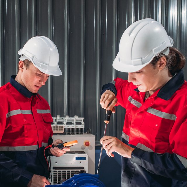 Two technician are performing an electrical safety evaluation on an industrial robot as part of routine quality control and maintenance procedures.