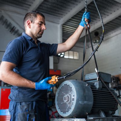 Mechanic operating a hoist to lift a compressor engine