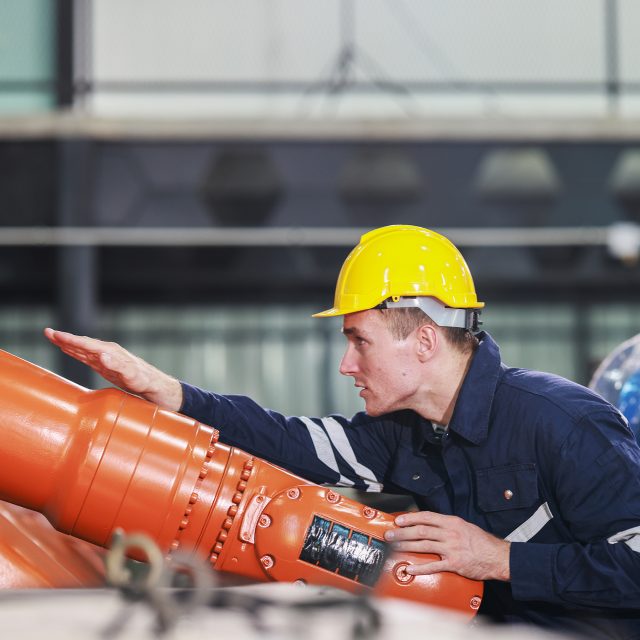 Robotic engineers conducting quality control and maintenance by examining, testing, and repairing robotic arms in a high-tech facility. Precision engineering, technology, automation, innovation