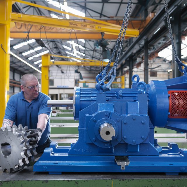 Engineer assembling industrial gearbox in engineering factory
