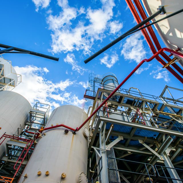 Low angle view of storage tanks and industrial piping at biofuel plant